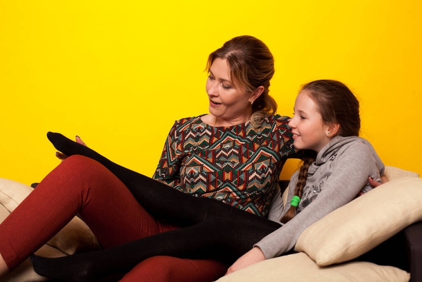 Мама и дочь сидят на диване в семейной комнате любви - Фото, изображение
