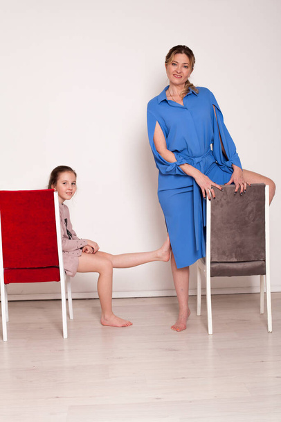 liefde familie mam en dochter zitten op stoelen in wit kamer - Foto, afbeelding