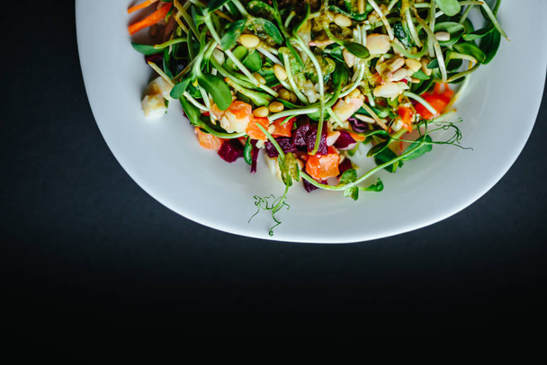 fresh organic green salad with arugula on a white plate and black background - Foto, imagen