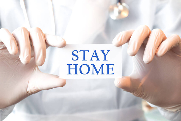 Arzt hält eine Karte mit Text STAY HOME in beiden Händen. Medizinisches Konzept, - Foto, Bild