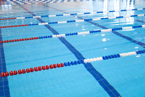 На заднем плане - бассейн с голубой водой и размеченными дорожками для плавания - Фото, изображение