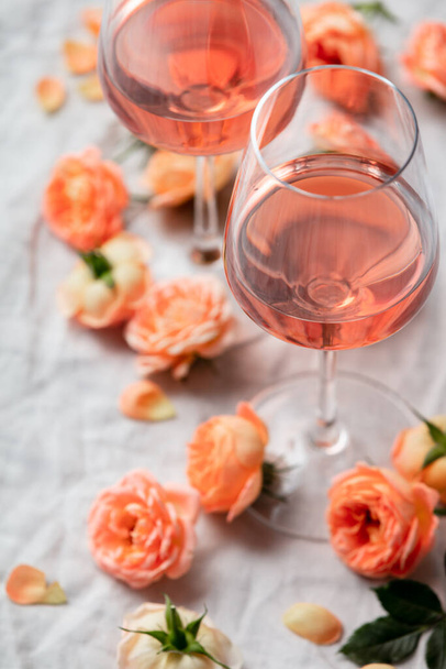 Rose wine in glasses and roses on white background, flat lay - Valokuva, kuva