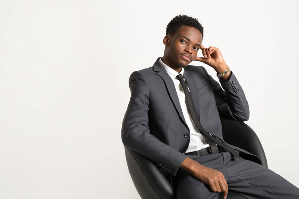 schöner junger afrikanischer Mann im Anzug auf weißem Hintergrund im Sessel - Foto, Bild