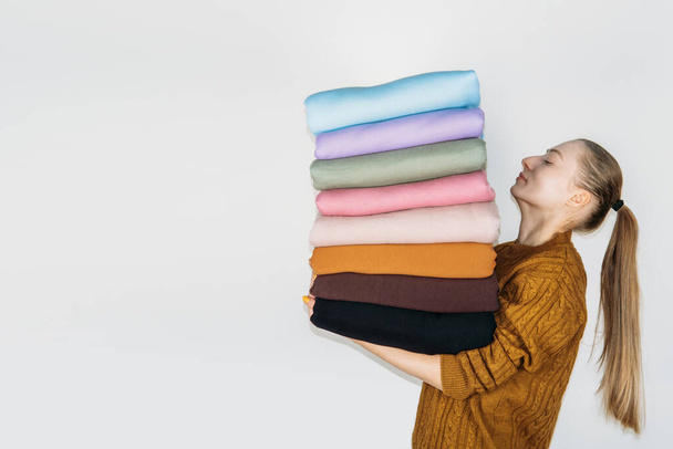 Woman holding Stack of Pastel natural color Fabrics on white background. Fabrics And Clothing Arranged In Neat Stacks. Fabrics pile background - Foto, afbeelding