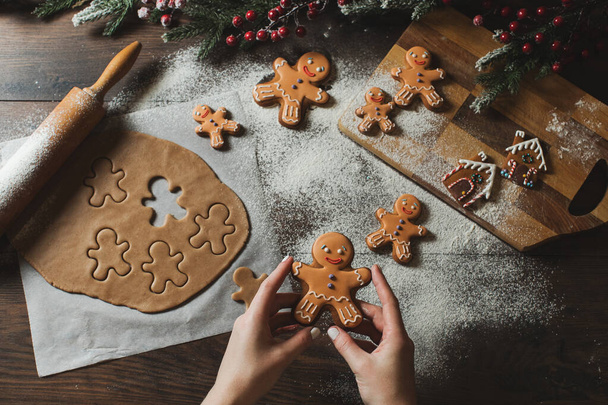 Christmas gift gingerbread on dark background. Woman is holding Christmas gingerbread cookies with icing sugar. Top view - Fotoğraf, Görsel