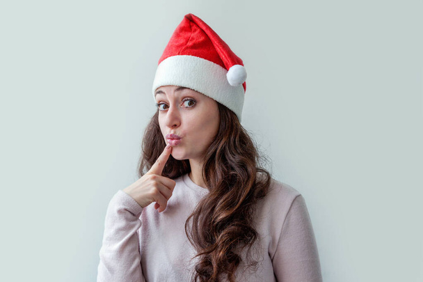 Beautiful girl with long hair in red Santa Claus hat isolated on white background looking happy and excited. Young woman portrait, true emotions. Happy Christmas and New Year holidays - Valokuva, kuva