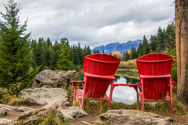 dos sillas rojas al lado de un lago con vista a la montaña - Foto, imagen