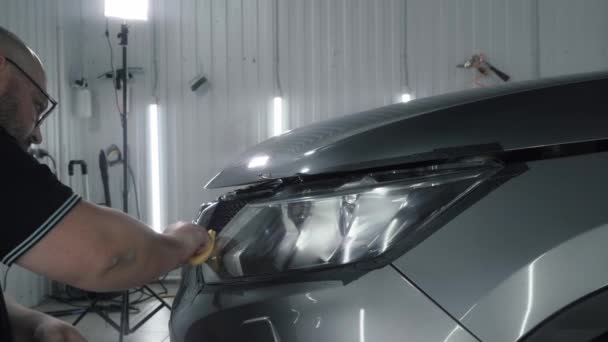 Service worker polishes headlights. Car detailing concept - Footage, Video