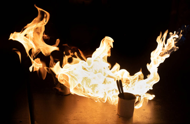 Lenguas de llama alrededor de una taza de metal con café, la bebida se prepara de acuerdo con una receta especial. - Foto, imagen