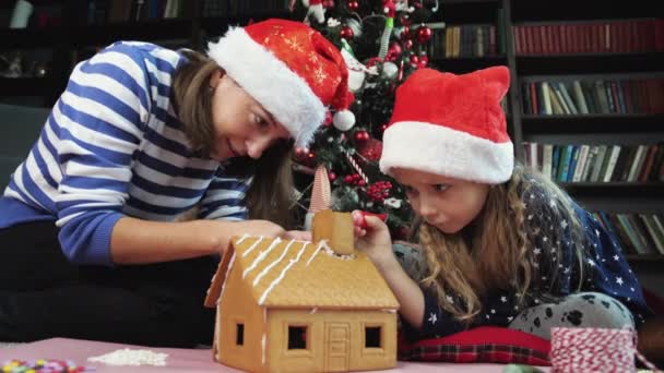 Frau und kleines Mädchen schmücken Lebkuchenhaus - Filmmaterial, Video
