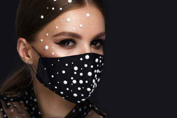 Portrait of a beautiful woman in a black mask with pearls and classic makeup. Mask mode during the covid pandemic - Foto, Imagem