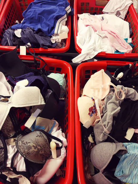 Vêtements et buanderie dans des paniers en plastique rouge dans un magasin de vêtements - Photo, image