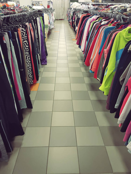 Des vêtements colorés suspendus sur une étagère dans un magasin de vêtements - Photo, image