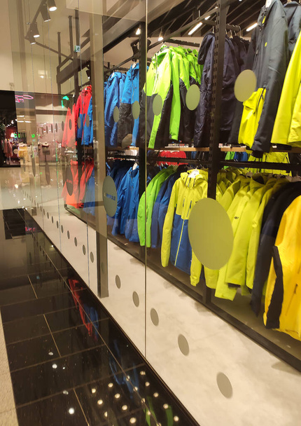 Красочная одежда висит на полке в магазине одежды - Фото, изображение