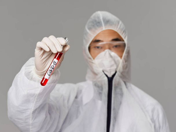 Άνδρας βοηθός εργαστηρίου προστατευτική ενδυμασία που ερευνά την ανάπτυξη ενός εμβολίου του κορωναϊού - Φωτογραφία, εικόνα