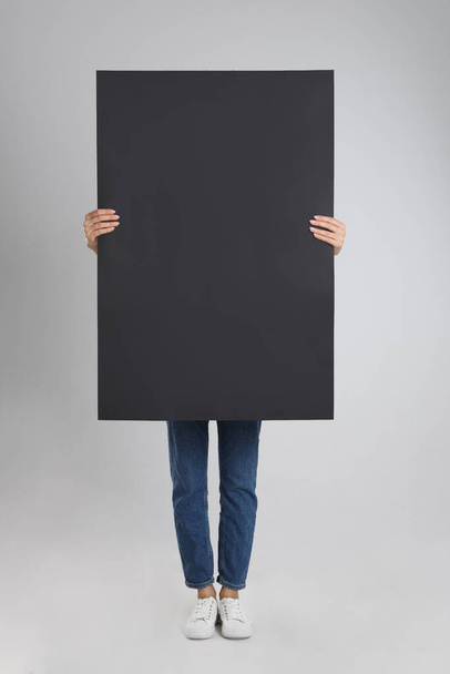 Woman holding blank poster on light grey background - Foto, Imagem