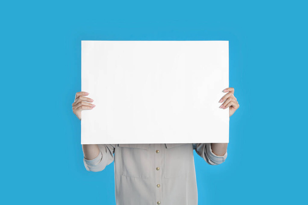 Woman holding blank poster on blue background - Photo, Image