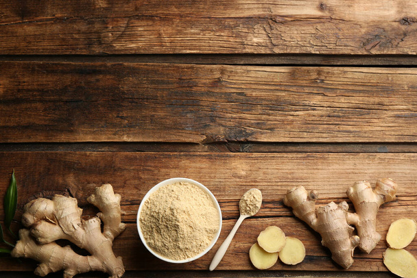 Dry ginger powder and fresh root on wooden table, flat lay. Space for text - Foto, imagen