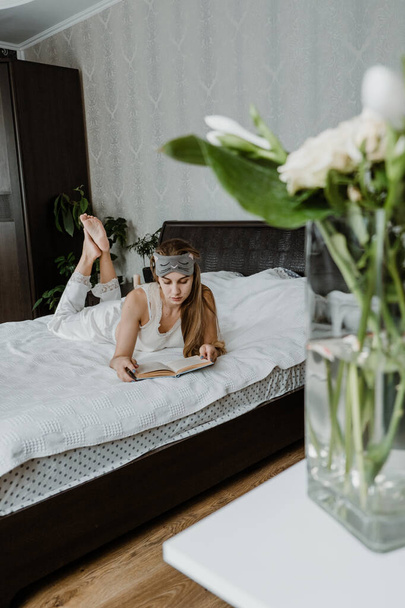 Self care, mourning routine, morning pages journal, day planning. Self Care Ideas for woman. Care Routine, Ways to Reduce Stress, increase mindfulness. Young woman lies on the bed and looks at book - Fotó, kép