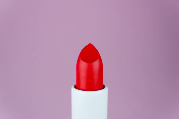 Roter Lippenstift in Nahaufnahme auf lila Hintergrund. Minimales Schönheitskonzept - Foto, Bild