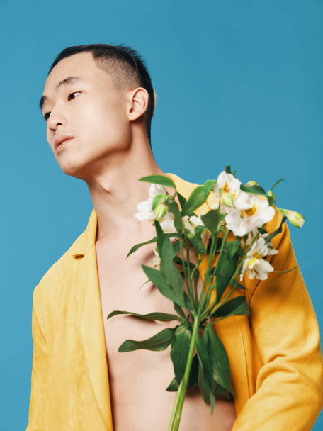 romantic asian man on blue background with bouquet of white flowers cropped view close-up romance - Fotó, kép