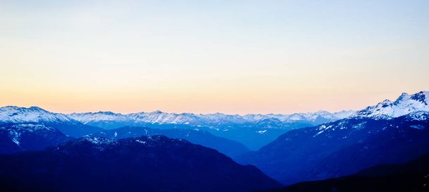 Kilátás a sötét hegycsúcsra alkonyatkor Brit Columbia, Kanada. - Fotó, kép