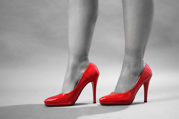 Επιλεκτικό κόκκινο χρώμα. Πόδια με κόκκινα ψηλά τακούνια από νεαρή όμορφη γυναίκα. Γυναικεία πόδια με κόκκινα ψηλά τακούνια - Φωτογραφία, εικόνα