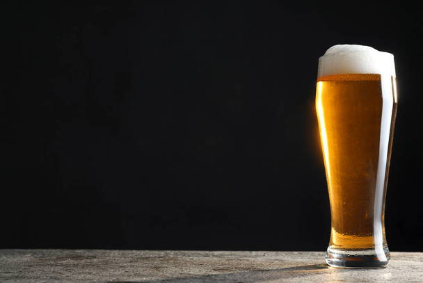 Cold tasty beer on grey table against dark background. Space for text - Foto, Imagen