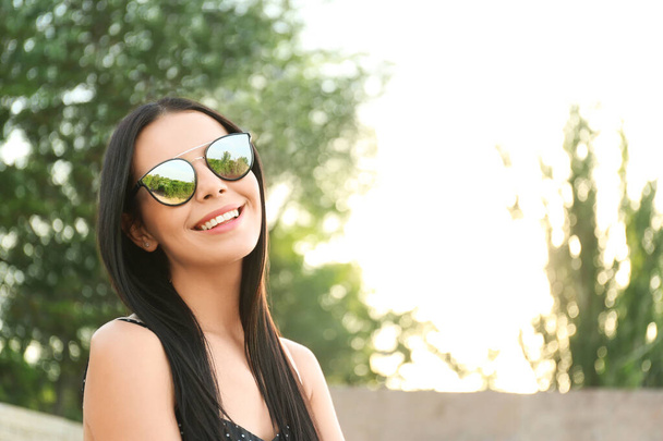Beautiful young woman wearing stylish sunglasses outdoors. Space for text - Fotó, kép