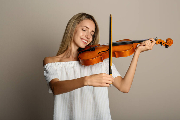 Beautiful woman playing violin on beige background - Fotoğraf, Görsel