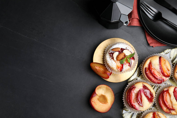 Delicious cupcakes with plums on black table, flat lay. Space for text - Фото, зображення