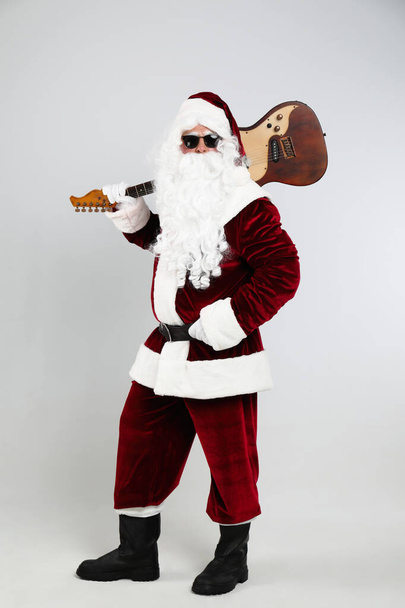 Santa Claus with electric guitar on light grey background. Christmas music - Photo, image