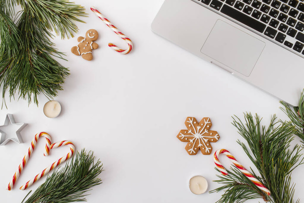 Christmas, winter, new year composition. Home office desk workspace with Fir tree branches, gingerbread, candies, candles on white background. Flat lay, top view, copy space - Foto, Imagem