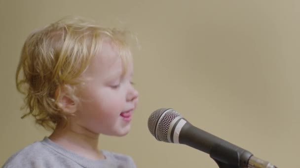 Cute little girl śpiewać piosenkę do mikrofonu, zabawny maluch korzystających z nadawania - Materiał filmowy, wideo