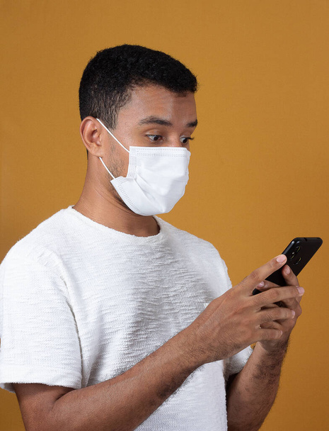 scared man wearing  mask  with cellphone in his hands - Photo, Image
