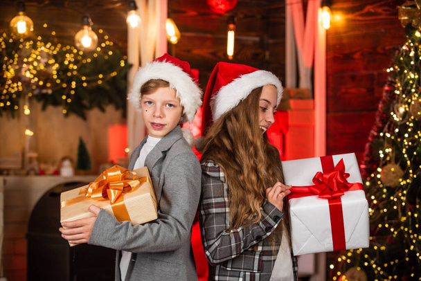 Family Christmas tradition. Kids lovely friends meet Christmas holiday. Sister and brother with gift boxes. Dreams come true. Festive atmosphere christmas eve. Boy and girl santa claus hats - Fotografie, Obrázek