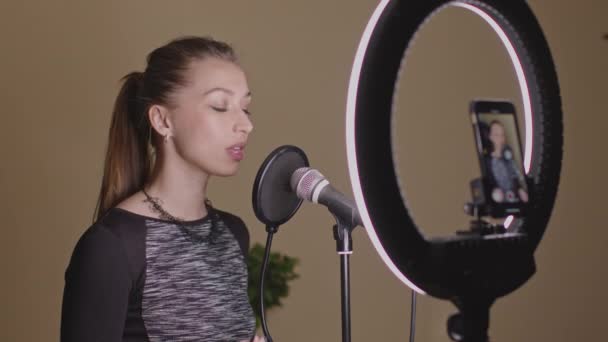 Piękny wokalista śpiewa piosenkę w mikrofonie, nagrywa samouczek muzyczny - Materiał filmowy, wideo