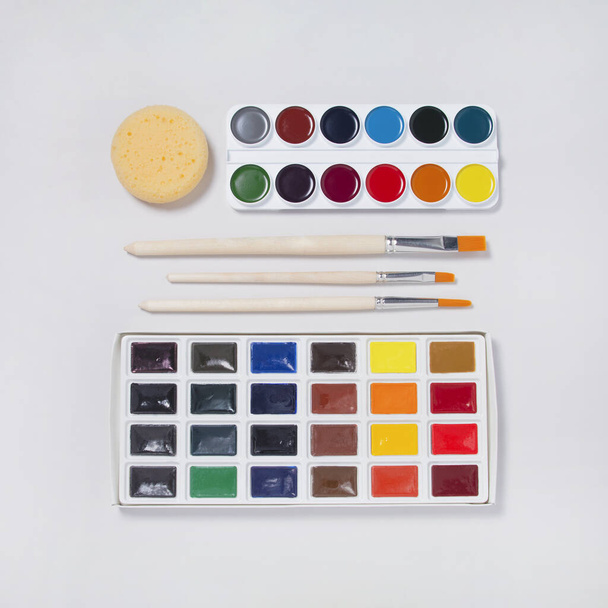 Набор акварельных красок, кисти на белом фоне - Фото, изображение