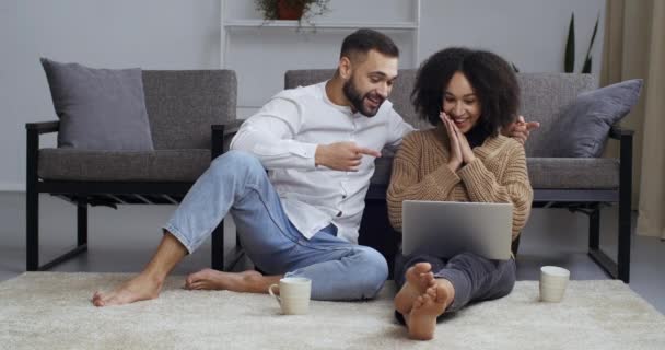 Çok ırklı beyaz erkek ve Afro-Amerikan melez kız yan yana oturmuş dizüstü bilgisayara bakıyorlar iyi haberleri okuyun zafer ödülü sevinci, zafer konsepti - Video, Çekim
