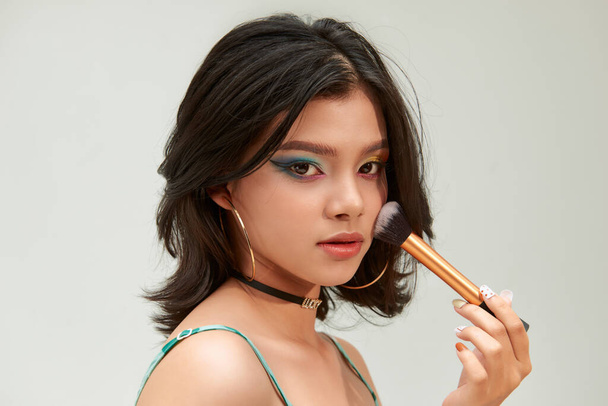Mujer Belleza con Cepillos de Maquillaje. Maquillaje natural para chica modelo asiática con sombra de ojos de arco iris. Cambio de imagen.  - Foto, Imagen