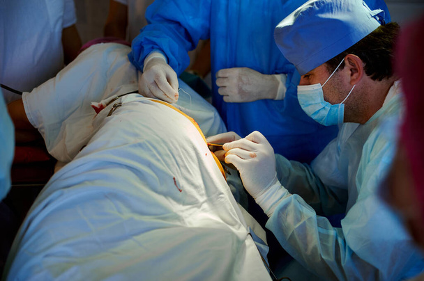 Хірургія. Вид збоку хірурга зшивання рани за допомогою хірургічного інструменту
. - Фото, зображення
