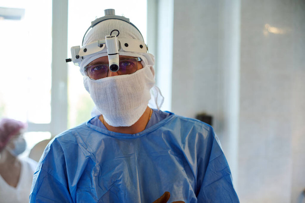 Portrét chirurga s reflektorem na operačním sále. Před operací. - Fotografie, Obrázek