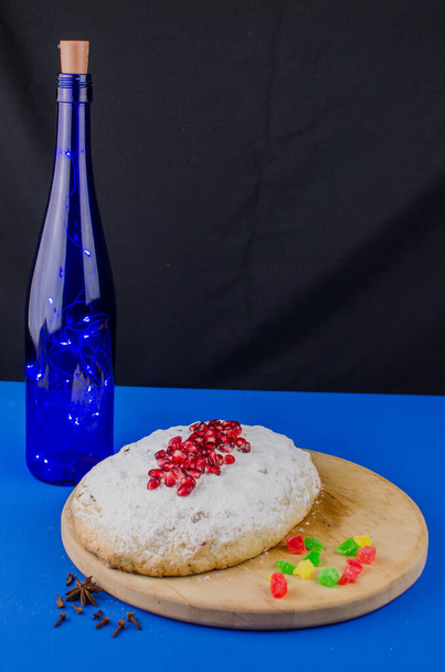 Joulukakku varastettu granaattiomenalla sinisellä pohjalla. Lomamakeiset - Valokuva, kuva
