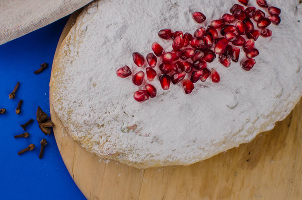 Christmas cake stolen with pomegranate on a blue background. Holiday sweets - Photo, image