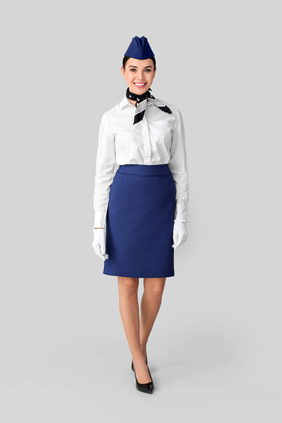 Mooie stewardess op grijze achtergrond - Foto, afbeelding