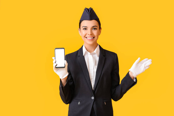 Beautiful stewardess with mobile phone on color background - Photo, Image