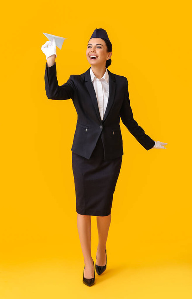 Beautiful stewardess with paper airplane on color background - 写真・画像
