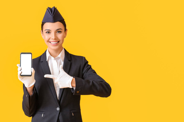 Beautiful stewardess with mobile phone on color background - Photo, Image