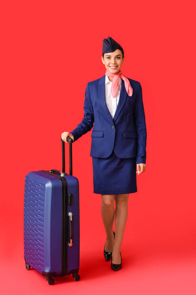 Beautiful stewardess with luggage on color background - Фото, зображення