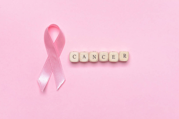 Palabra CANCER con cinta rosa sobre fondo de color - Foto, imagen